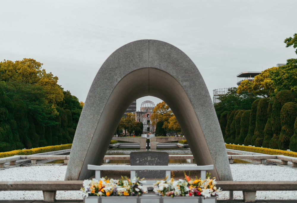 Bogen über dem Kenotaph im Friedenspark von Hiroshima mit Blick auf die Atombombenkuppel